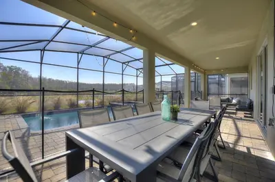 a patio with a table and chairs and a pool at Water Kingdom Storey Lake by Shine Villas! #525 home in Kissimmee