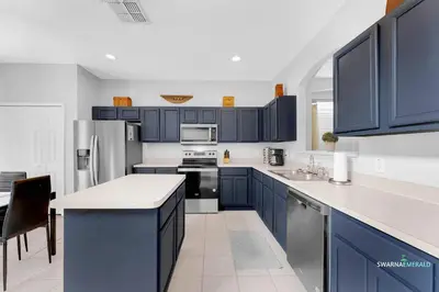 a kitchen with blue cabinets and white counter tops at Private Pool, Spa Tub, Themed Rooms, Resort Amenities in Kissimmee