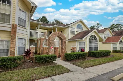 a house with a brick archway in front of it at Laguna Bay 2 Bedroom Condo Resort Pool 8 Miles to Disney in Kissimmee