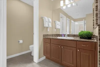 a bathroom with a sink and a toilet and a mirror at The Point, Lux Apartment 4 min from Universal in Orlando