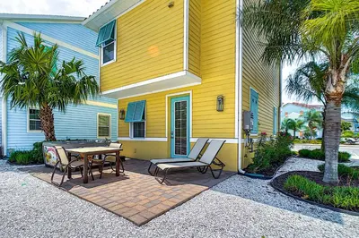 a yellow house with a patio with a table and chairs at Tropical Cottage with Hot Tub Near Disney! in Orlando
