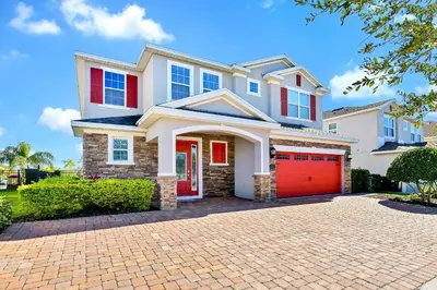a house with a red garage on a brick driveway at Vibrant Home Near Disney With Private Pool, Waterpark And Resort Acces At Encore Resorts Reunion - 221Fl in Kissimmee