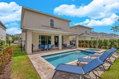 a home with a swimming pool and two lounge chairs at 7462 Themed Villa 6BD - Pool Spa-Game room in Orlando