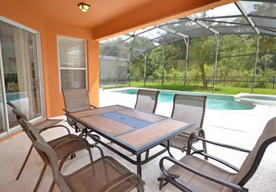 a patio with a table and chairs and a swimming pool at Summer Sparkle home in Kissimmee