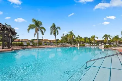 a large swimming pool with palm trees in the background at Summer Sparkle home in Kissimmee