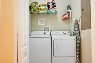 a laundry room with a washing machine and a shelf with towels at Majestic Retreat townhouse in Kissimmee