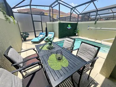 a patio with a table and chairs next to a swimming pool at Majestic Retreat townhouse in Kissimmee