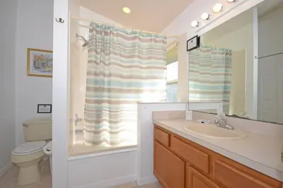 a bathroom with a sink and a toilet and a mirror at Sweet Magnolia home in Orlando