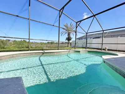 a swimming pool with blue water in a building at Sweet Magnolia home in Orlando