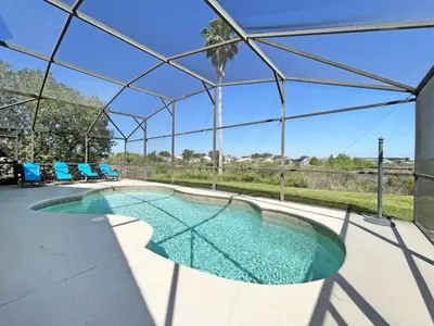 a swimming pool with blue chairs and a tent at Sweet Magnolia home in Orlando