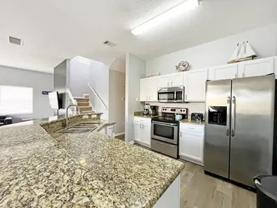 a kitchen with stainless steel appliances and white cabinets at Villa Azul townhouse in Kissimmee