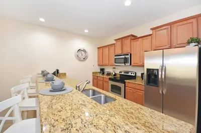 a kitchen with a stainless steel refrigerator and wooden cabinets at California Palms condo in Kissimmee