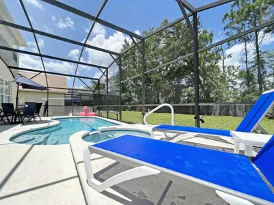 a swimming pool with blue and white chairs next to a house at Hideaway Dream home in Kissimmee