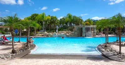 a swimming pool with a waterfall in a resort at Bamboo Palm home in Kissimmee