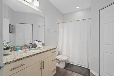 a white bathroom with a toilet and a sink at Beautiful & Cozy 4bd Home, Gated Community in Kissimmee