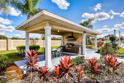 a pavilion with a kitchen in a backyard with palm trees at Beautiful & Cozy 4bd Home, Gated Community in Kissimmee