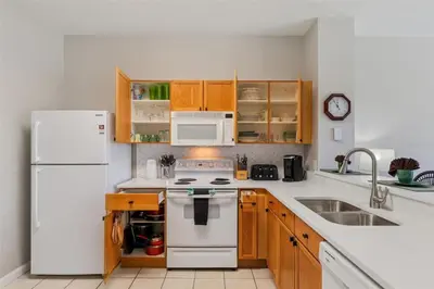 a kitchen with white appliances and wooden cabinets at Veteran Owned 3bdr/3 bath Townhouse w/WiFi 3mi to Disney - Winter/Spring Specials in Kissimmee