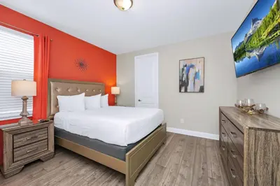 a bedroom with a bed and an orange wall at Alluring Home Near Disney With Themed, Media And Game Room With Waterpark & Resort Access At Encore Resorts Reunion - 232Au in Kissimmee
