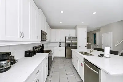 a large white kitchen with white cabinets and appliances at Alluring Home Near Disney With Themed, Media And Game Room With Waterpark & Resort Access At Encore Resorts Reunion - 232Au in Kissimmee