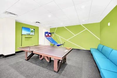 a ping pong table in a room with a blue couch at 3BR Condo with Pool - Near Disney in Orlando