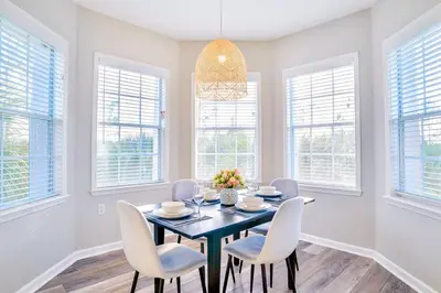 a dining room with a table and chairs and windows at 3BR Condo with Pool - Near Disney in Orlando