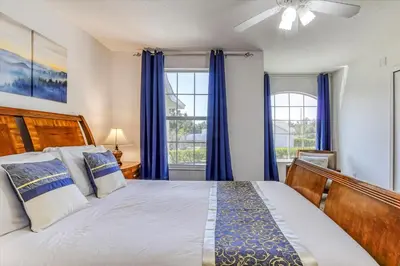 a bedroom with a bed and two windows with blue curtains at Large Home-Private Pool, Spa, and Pet Friendly Sleeps 12 in Orlando