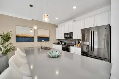 a kitchen with a stainless steel refrigerator and white cabinets at Amazing Story Lake Town Home With Pool townhouse in Kissimmee