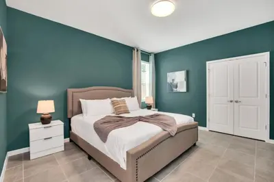 a bedroom with a blue accent wall and a bed at The Ultimate New 15 Bedroom 16 Bathroom Vernada villa in Kissimmee