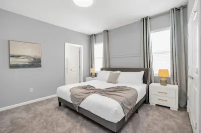 a white bedroom with a bed and windows at The Ultimate New 15 Bedroom 16 Bathroom Vernada villa in Kissimmee