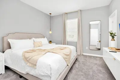 a white bedroom with a bed and a mirror at The Ultimate New 15 Bedroom 16 Bathroom Vernada villa in Kissimmee