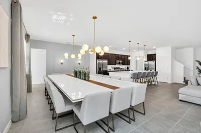 a dining room and kitchen with a white table and chairs at The Ultimate New 15 Bedroom 16 Bathroom Vernada villa in Kissimmee