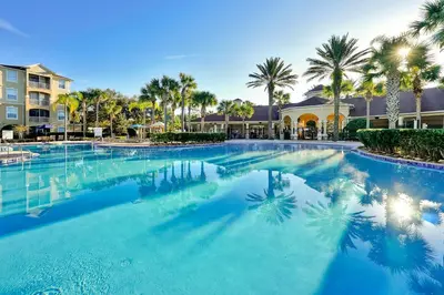 a large swimming pool with palm trees and condos at Windsor Hills Resort Poolside Ground Floor 3 Bed Condo in Orlando