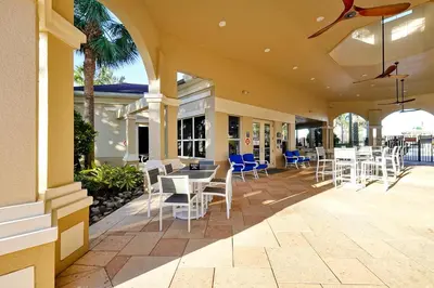 a patio with white chairs and tables on a building at Windsor Hills Resort Poolside Ground Floor 3 Bed Condo in Orlando