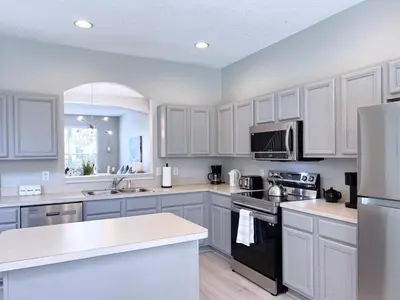 a kitchen with white cabinets and a black appliance at Spacious 7Bd Pool Gm Hm Terra Verde Resort-211HBL home in Kissimmee