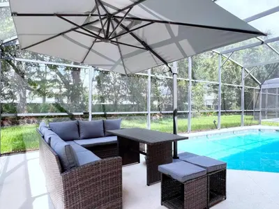 a patio with a table and umbrella next to a pool at Spacious 7Bd Pool Gm Hm Terra Verde Resort-211HBL home in Kissimmee