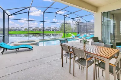 a patio with a table and chairs and a pool at 6BR Luxury Home w Pool Hot Tub and Games room in Kissimmee