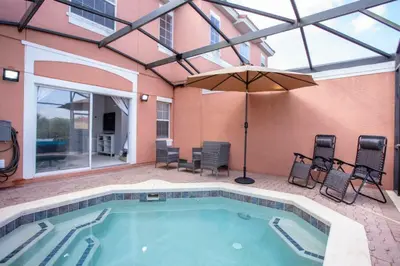 a swimming pool with an umbrella and chairs at Amazing 3 Bdrms At Encantada- 6 miles from Disney in Kissimmee