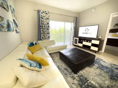 a living room with a white couch and a flat screen tv at Comfortable Apart 4Bdrm3Bath- 4 miles to Disney in Orlando
