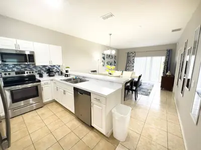 a kitchen with white cabinets and a dining room at Comfortable Apart 4Bdrm3Bath- 4 miles to Disney in Orlando