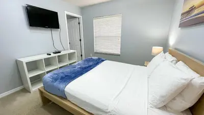 a bedroom with a white bed and a flat screen tv at Amazing 3 Bdrm At Encantada- 6 miles from Disney in Kissimmee