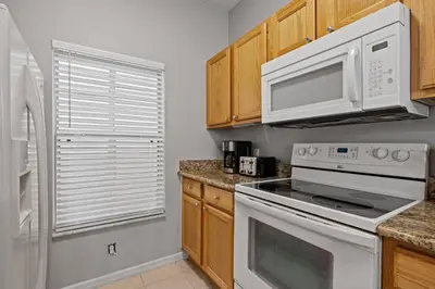a kitchen with white appliances and wooden cabinets at Amazing 3Bdrms At Encantada -6 miles from Disney in Kissimmee