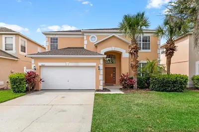 a house with a garage and palm trees at Family Friendly Emerald Island Resort Vacation Home with Private Pool and Spa Near Disney in Kissimmee
