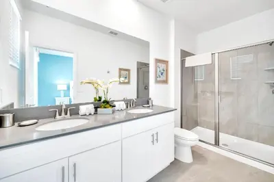 a white bathroom with two sinks and a shower at Upstay 6BR Resort Home w Pool & Basketball Court in Kissimmee