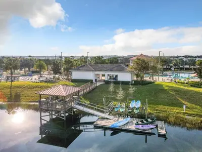 a dock with boats on the water in front of a house at Upstay 6BR Resort Home w Pool & Basketball Court in Kissimmee