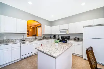 a large kitchen with white cabinets and a counter top at Emerald Island Escape- Pool and spa in Kissimmee
