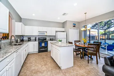 a kitchen with white cabinets and a table and chairs at Emerald Island Escape- Pool and spa in Kissimmee
