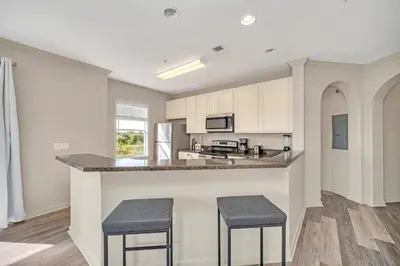 a kitchen with white cabinets and a counter with stools at Condo w Pool, Games Room - Pet Friendly in Orlando