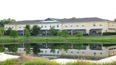 a large white building with a reflection in the water at Coral Cay - 4 Bed 3 Baths Townhome in Kissimmee