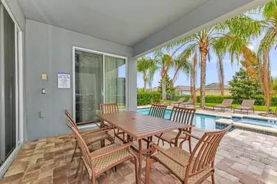 a patio with a table and chairs and a pool at Vibrant Home Near Disney With Private Pool, Game Room And Waterpark & Resort Access At Encore Resorts Reunion - 7572Mr in Kissimmee