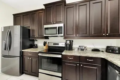 a kitchen with wooden cabinets and stainless steel appliances at Vibrant Home Near Disney With Private Pool, Game Room And Waterpark & Resort Access At Encore Resorts Reunion - 7572Mr in Kissimmee